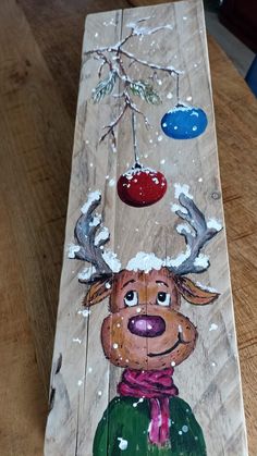 a wooden plank with a painting of a deer on it's face and antlers hanging from the top