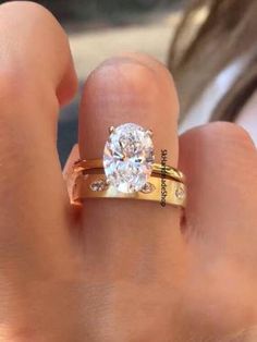 a close up of a person's hand with a diamond ring on their finger