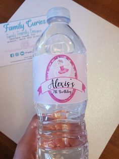 a hand holding a bottle of water with labels on the front and back of it