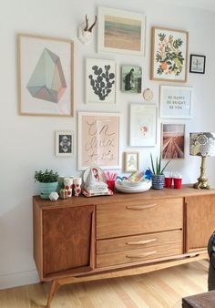 a living room filled with lots of pictures on the wall above a wooden dresser and coffee table