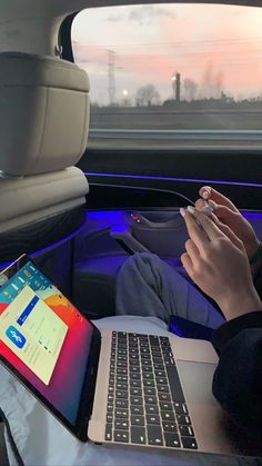 a person sitting in the back seat of a car using a laptop computer