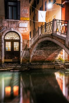 a bridge over a body of water next to a tall brick building with arched windows