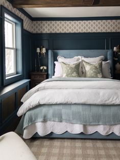 a large bed sitting in a bedroom next to a window with two lamps on either side of it