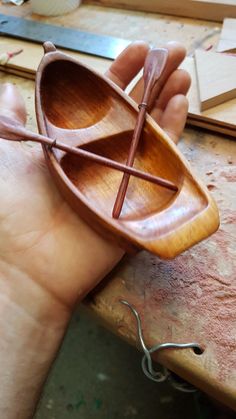 a hand holding a small wooden boat on top of a table