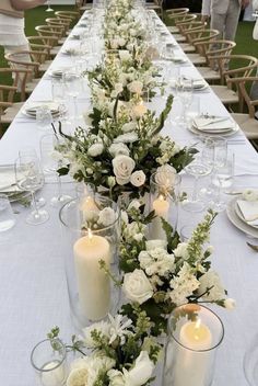 a long table with white flowers and candles on it is set for a formal dinner