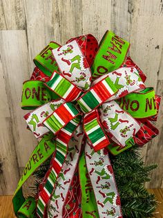 a green and red christmas bow on top of a tree