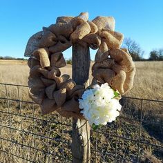 a wreath is placed on top of a fence post with white flowers in front of it