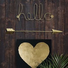 there is a heart and an arrow hanging on the wall next to a potted plant