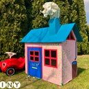 a child's play house with a toy car in the yard