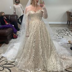 a woman in a wedding dress is taking a selfie with her cell phone while another person looks on