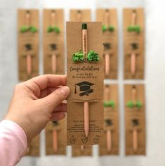 a person holding up a brown package with green decorations on it and some pencils in the background