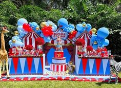 a circus themed birthday party with balloons, cake and giraffes in the grass