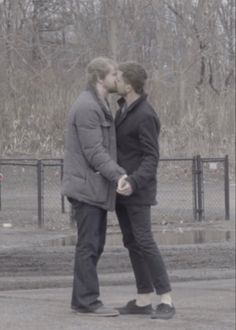 two people standing next to each other kissing