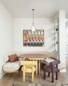 a dining room table with chairs and a bench in front of an art piece on the wall