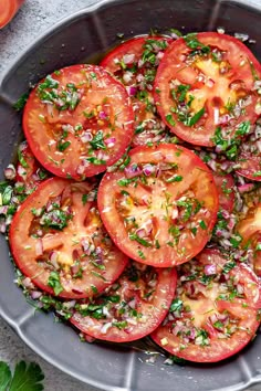 sliced tomatoes in a bowl with herbs and seasoning on the top, ready to be eaten