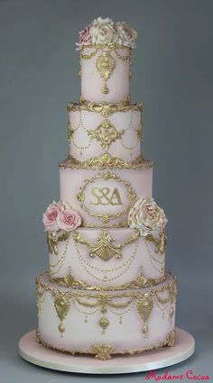 a pink and gold wedding cake with flowers on it's tiers, sitting on top of a white plate