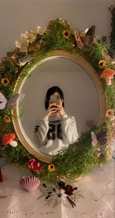 a woman taking a selfie in front of a mirror with flowers and butterflies around her