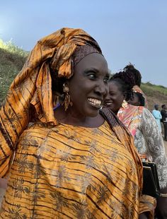 a woman in an orange and black dress smiles at the camera while others look on