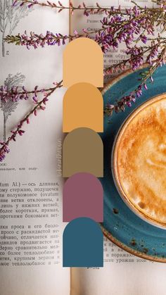 a cup of coffee sitting on top of a blue plate next to a book and purple flowers