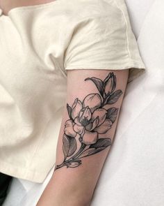 a woman's arm with a flower tattoo on the left side of her arm