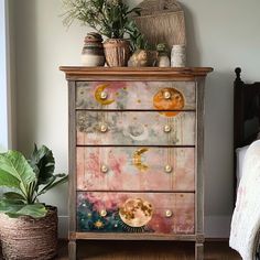 an old dresser has been decorated with colorful paint and gold hardware, along with potted plants