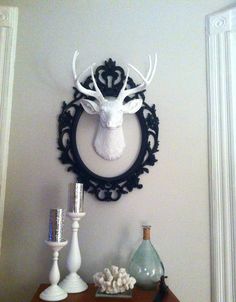 a deer head mounted to the side of a wall next to candles and vases