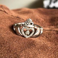 a close up of a ring on a brown blanket with diamonds in the middle and an open heart at the center