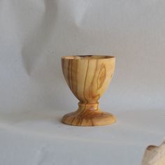 a small wooden cup sitting on top of a white cloth covered table next to a rock