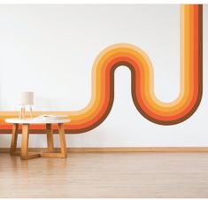 an orange and yellow wave wall decal next to a table with a lamp on it