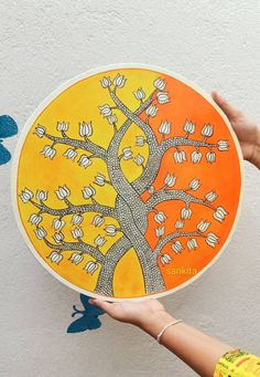 a person holding up an orange and yellow plate with a tree painted on the side