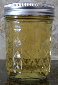 a glass jar filled with yellow liquid sitting on top of a marble counter next to a tile wall