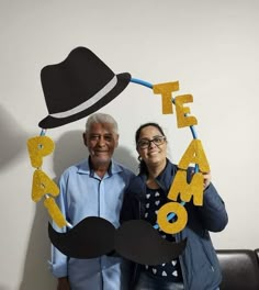 two people standing next to each other holding up letters