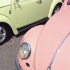 two cars parked next to each other in a parking lot, one is pink and the other is green