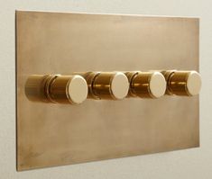 three round knobs are mounted to the side of a gold plated light switch