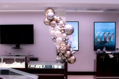 a bunch of balloons hanging from the ceiling in a room with tvs and other decorations