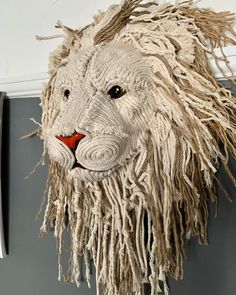 a white lion head hanging on the side of a wall next to a gray refrigerator