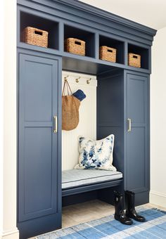 an entryway with blue painted cabinets and baskets on the top shelf, along with black rubber boots