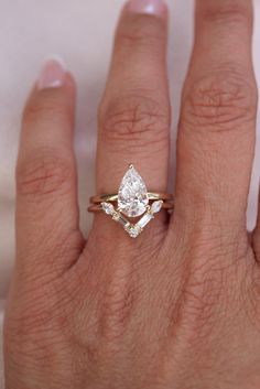 a woman's hand with a diamond ring on top of her finger and an engagement band