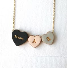 three heart shaped necklaces with the word mama written on one side and two hearts in the other