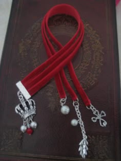 a book with a red ribbon attached to it and charms hanging from the clasps