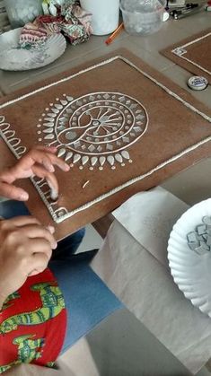 two people are making decorative paper plates on the table