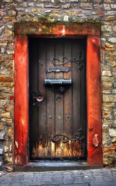 an old wooden door with iron bars on the front and side, surrounded by stone walls