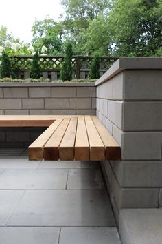 a wooden bench sitting on top of a cement block covered patio next to a brick wall