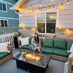 a woman sitting on a couch in front of a fire pit with lots of lights