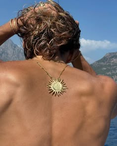 the back of a man wearing a gold sun necklace