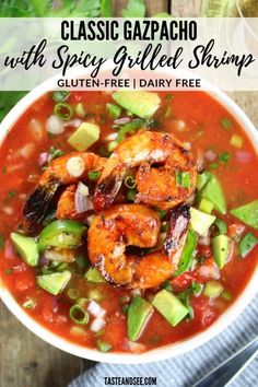 a bowl filled with shrimp, avocado and tomato soup on top of a wooden table