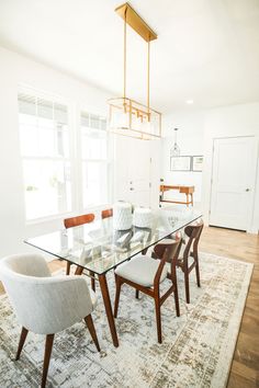 a dining room table with chairs and a rug in front of the window is shown