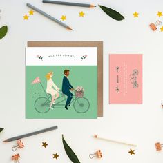 a couple is riding a bike together on the same card as they are surrounded by stationery and pencils