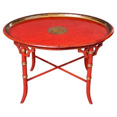 a red table with gold trimmings and a round tray on it's legs