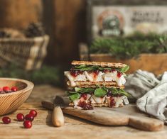 a sandwich cut in half sitting on top of a cutting board next to cranberry sauce